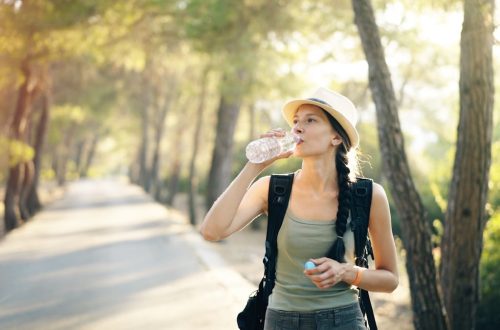 a woman in a hat drinking water from a bottle