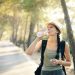 a woman in a hat drinking water from a bottle